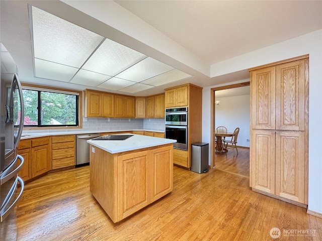 412 Doe Run Rd, Sequim, WA 98382 - kitchen with stainless steel appliances, light countertops, a center island, light wood finished floors, and decorative backsplash