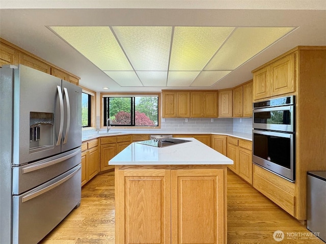 412 Doe Run Rd, Sequim, WA 98382 - kitchen with appliances with stainless steel finishes, light wood-type flooring, light countertops, decorative backsplash, and a center island