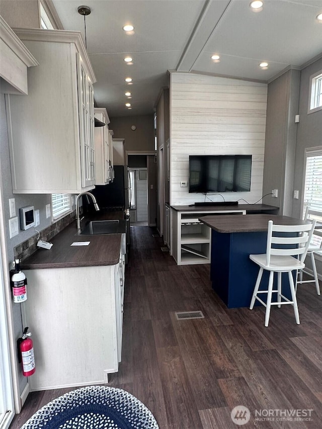 20 Golden Sands Pl, Sequim, WA 98382 - kitchen with dark countertops, dark wood-type flooring, recessed lighting, a breakfast bar area, and white cabinets