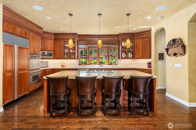 24817 NE 20th St, Sammamish, WA 98074 - bar featuring built in appliances, arched walkways, decorative backsplash, dark wood-style floors, and pendant lighting