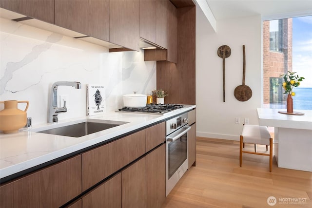 121 Stewart St Unit 1407, Seattle, WA 98101 - kitchen with light wood finished floors, appliances with stainless steel finishes, light stone counters, and tasteful backsplash