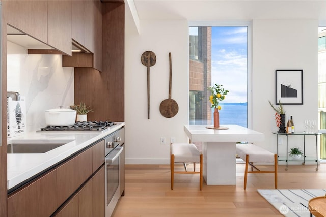 121 Stewart St Unit 1407, Seattle, WA 98101 - kitchen with light wood-style flooring, stainless steel appliances, light countertops, and tasteful backsplash