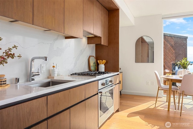 121 Stewart St Unit 1407, Seattle, WA 98101 - kitchen with appliances with stainless steel finishes, light wood finished floors, backsplash, and light countertops
