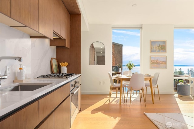 121 Stewart St Unit 1407, Seattle, WA 98101 - kitchen featuring light wood finished floors, backsplash, stainless steel appliances, and light countertops