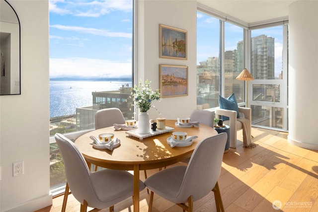 121 Stewart St Unit 1407, Seattle, WA 98101 - dining space with wood finished floors, expansive windows, a water view, and a city view