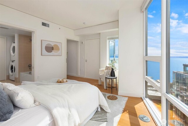 121 Stewart St Unit 1407, Seattle, WA 98101 - bedroom featuring stacked washer / dryer and light wood finished floors