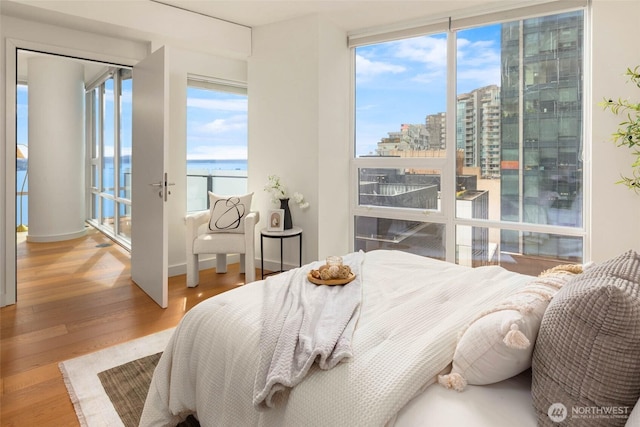 121 Stewart St Unit 1407, Seattle, WA 98101 - bedroom with wood finished floors, a water view, expansive windows, and a view of city