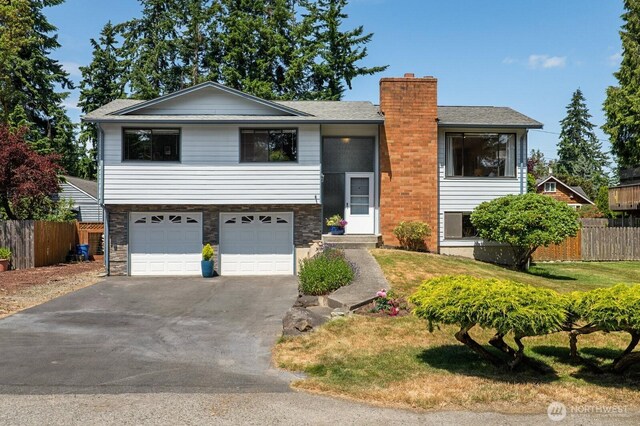 8815 221st Pl SW, Edmonds, WA 98026 - bi-level home with a garage, asphalt driveway, a chimney, roof with shingles, and stone siding