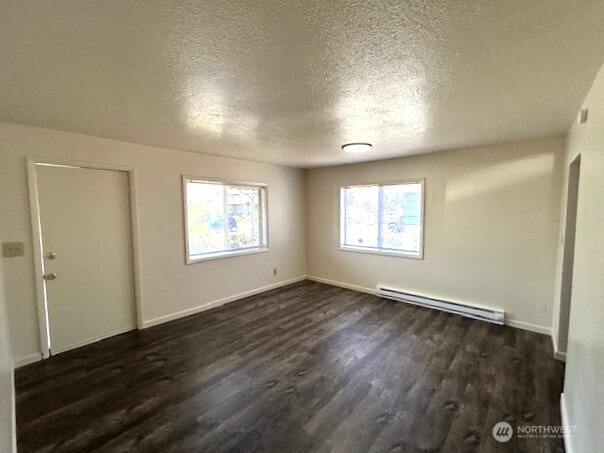 1004 8th, Longview, WA 98632 - empty room featuring a baseboard radiator, dark wood-style flooring, and a textured ceiling