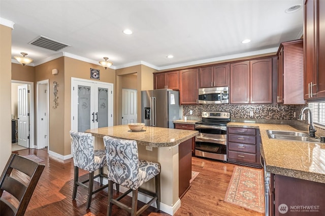9127 Periwinkle Loop NE, Olympia, WA 98516 - kitchen featuring stainless steel appliances, a breakfast bar, ornamental molding, tasteful backsplash, and wood finished floors