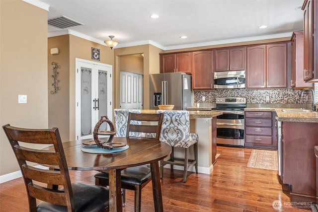 9127 Periwinkle Loop NE, Olympia, WA 98516 - kitchen featuring appliances with stainless steel finishes, ornamental molding, light wood-style flooring, a kitchen island, and tasteful backsplash