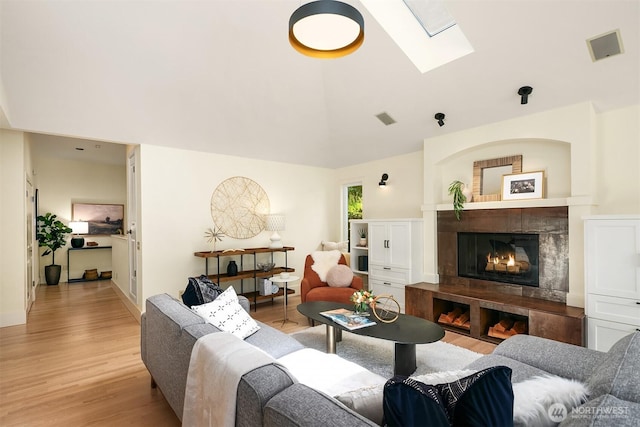 9201 24th Ave NW, Seattle, WA 98117 - living area featuring a skylight, light wood-type flooring, a tile fireplace, and vaulted ceiling