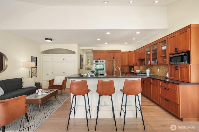 9201 24th Ave NW, Seattle, WA 98117 - kitchen with stainless steel appliances, light wood-type flooring, a breakfast bar, glass insert cabinets, and recessed lighting