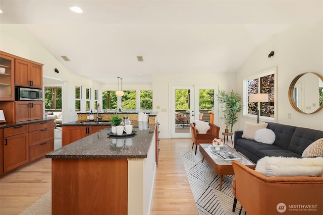 9201 24th Ave NW, Seattle, WA 98117 - kitchen featuring stainless steel microwave, vaulted ceiling, open floor plan, french doors, and light wood finished floors