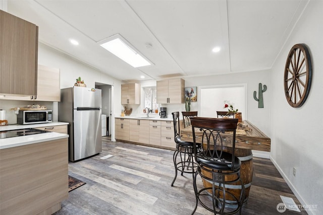 725 37th St SE Unit 36, Auburn, WA 98002 - kitchen featuring stainless steel appliances, wood finished floors, lofted ceiling, light countertops, and light brown cabinets