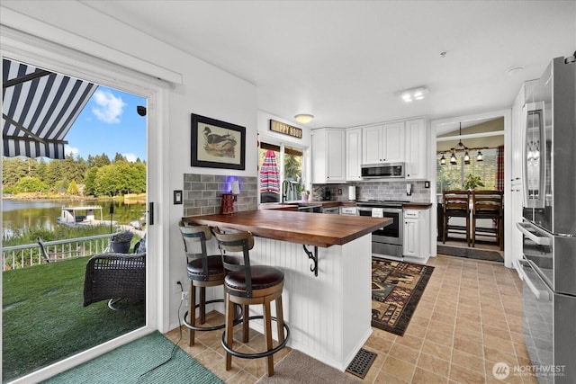32421 Whitman Lake Dr E, Graham, WA 98338 - kitchen featuring butcher block counters, tasteful backsplash, stainless steel appliances, a peninsula, and a water view