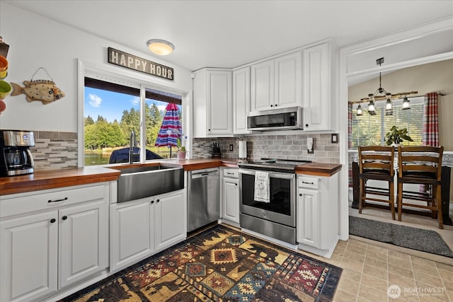 32421 Whitman Lake Dr E, Graham, WA 98338 - kitchen with butcher block counters, stainless steel appliances, decorative backsplash, and white cabinetry