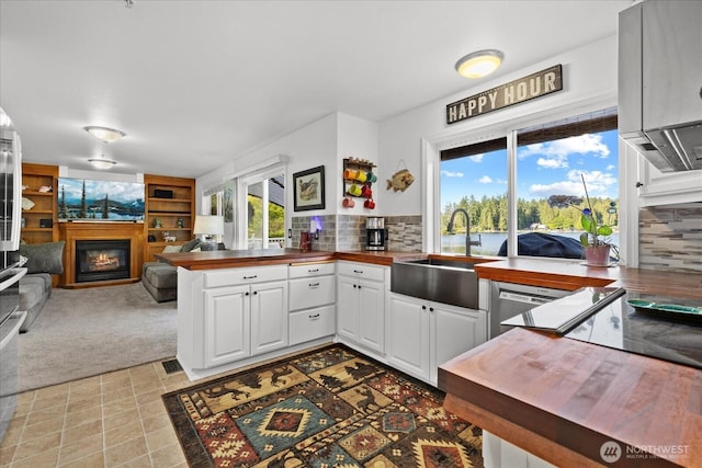 32421 Whitman Lake Dr E, Graham, WA 98338 - kitchen featuring wooden counters, a glass covered fireplace, open floor plan, a peninsula, and island exhaust hood