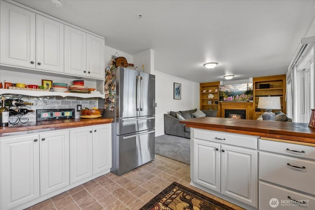 32421 Whitman Lake Dr E, Graham, WA 98338 - kitchen with open floor plan, a warm lit fireplace, freestanding refrigerator, wood counters, and white cabinets