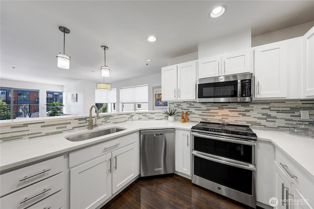 4026 Stone Way N Unit 501, Seattle, WA 98103 - kitchen featuring stainless steel appliances, backsplash, light countertops, white cabinetry, and decorative light fixtures