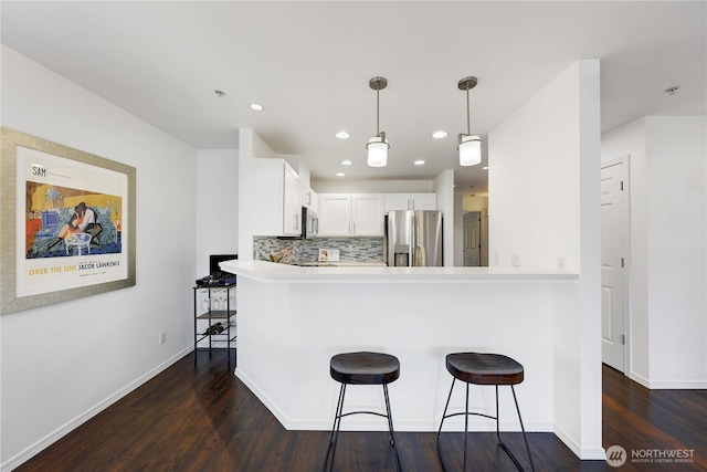 4026 Stone Way N Unit 501, Seattle, WA 98103 - kitchen featuring stainless steel appliances, dark wood-style flooring, decorative backsplash, a kitchen breakfast bar, and a peninsula