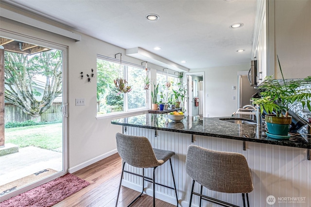 6301 Agnes Rd NE, Tacoma, WA 98422 - kitchen featuring dark stone counters, a peninsula, light wood-type flooring, recessed lighting, and white cabinetry