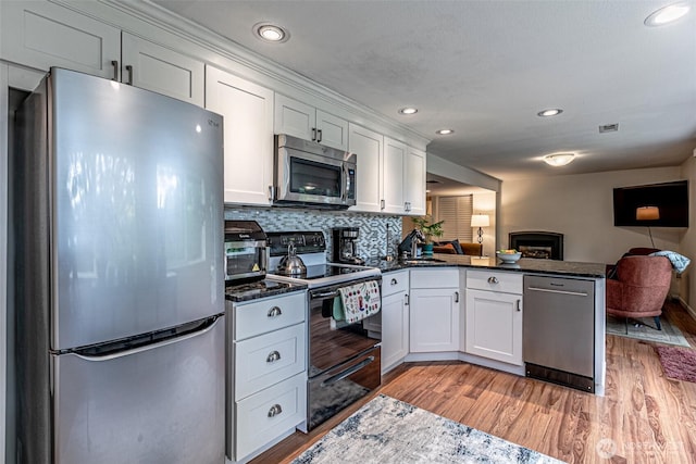 6301 Agnes Rd NE, Tacoma, WA 98422 - kitchen with stainless steel appliances, a peninsula, open floor plan, white cabinetry, and light wood finished floors