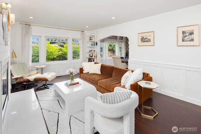 3249 27th Ave W, Seattle, WA 98199 - living area featuring dark wood-style flooring, a decorative wall, arched walkways, wainscoting, and a fireplace
