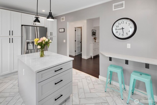 3249 27th Ave W, Seattle, WA 98199 - kitchen featuring stainless steel refrigerator with ice dispenser, recessed lighting, hanging light fixtures, white cabinetry, and a kitchen island