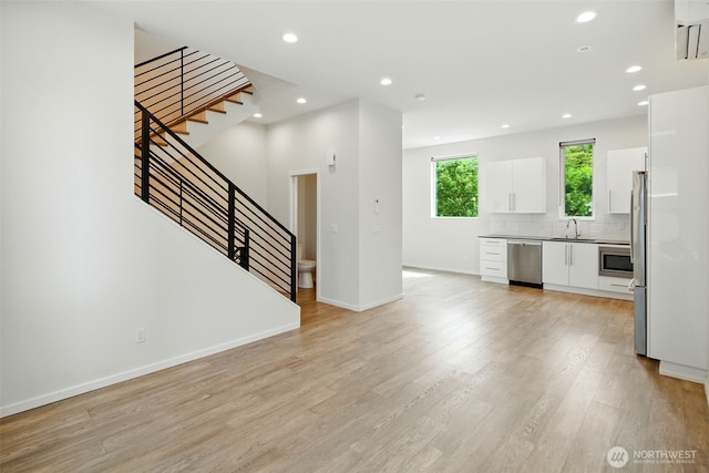 9732 Woodlawn Ave N Unit A, Seattle, WA 98103 - unfurnished living room with light wood-type flooring, stairs, and recessed lighting