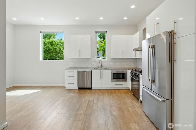 9732 Woodlawn Ave N Unit A, Seattle, WA 98103 - kitchen with appliances with stainless steel finishes, light wood finished floors, dark countertops, tasteful backsplash, and modern cabinets