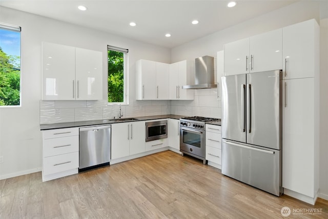 9732 Woodlawn Ave N Unit A, Seattle, WA 98103 - kitchen featuring stainless steel appliances, wall chimney exhaust hood, dark countertops, tasteful backsplash, and light wood-style flooring