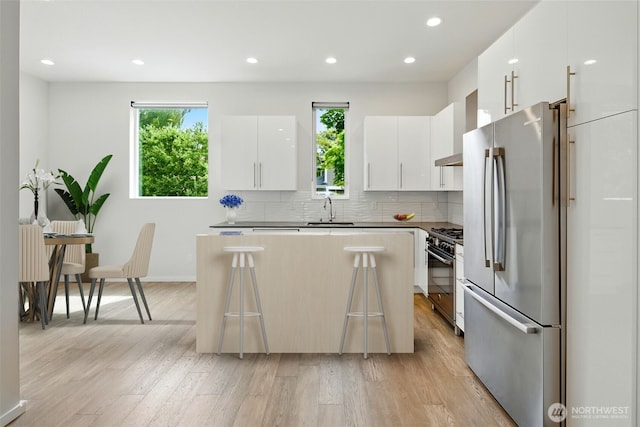 9732 Woodlawn Ave N Unit A, Seattle, WA 98103 - kitchen with stainless steel appliances, light wood-style flooring, modern cabinets, a center island, and tasteful backsplash