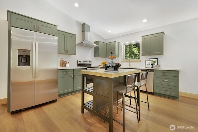 10405 Tahoma Dr, Anderson Island, WA 98303 - kitchen with green cabinetry, stainless steel appliances, wall chimney range hood, light countertops, and recessed lighting