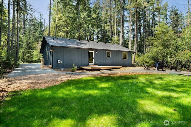 10405 Tahoma Dr, Anderson Island, WA 98303 - rear view of house featuring board and batten siding, a yard, a view of trees, and a patio area