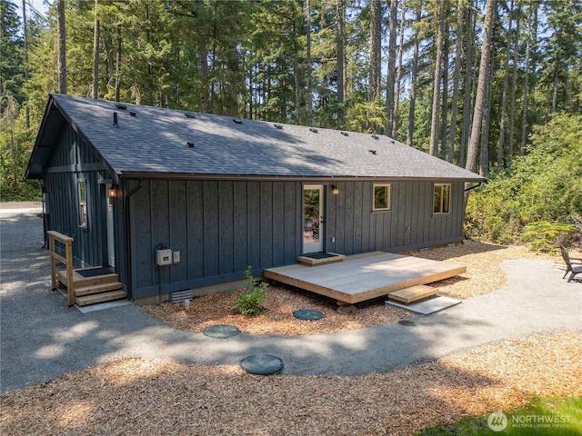 10405 Tahoma Dr, Anderson Island, WA 98303 - view of front of house featuring board and batten siding, a view of trees, and a shingled roof