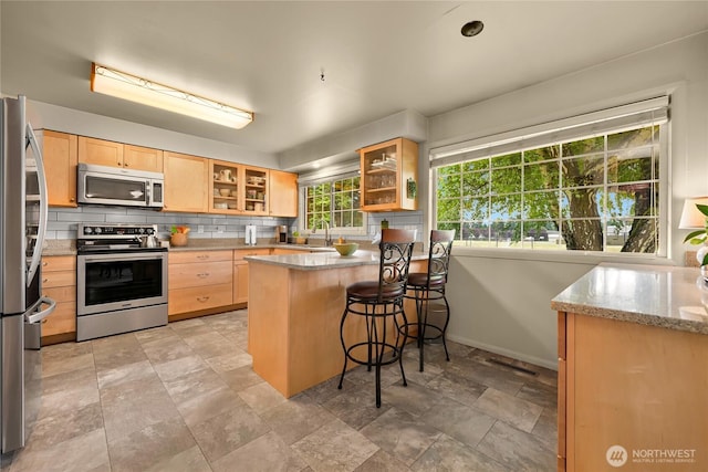 2714 Alderwood Ave, Bellingham, WA 98225 - kitchen featuring stainless steel appliances, light brown cabinets, a peninsula, stone finish floors, and backsplash