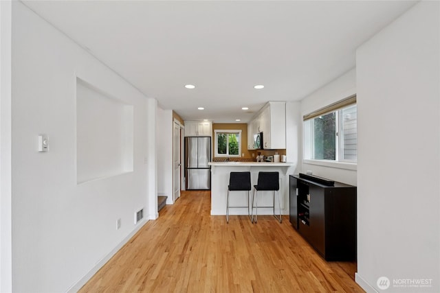 8450 25th Ave SW Unit B, Seattle, WA 98106 - kitchen with stainless steel appliances, white cabinetry, light wood-style flooring, a peninsula, and recessed lighting