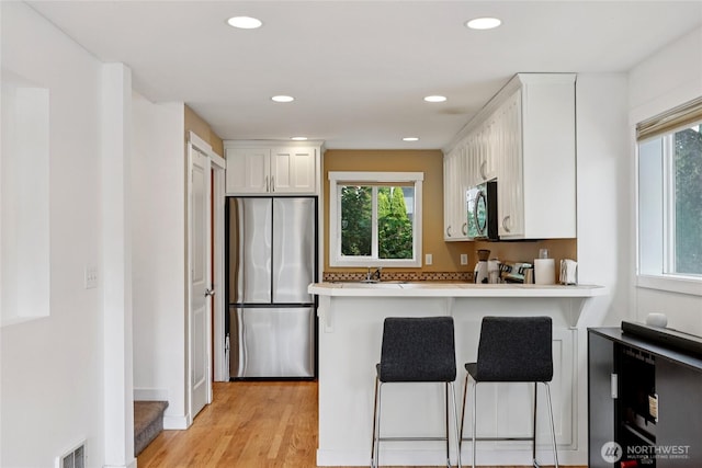 8450 25th Ave SW Unit B, Seattle, WA 98106 - kitchen with stainless steel appliances, white cabinets, healthy amount of natural light, and recessed lighting