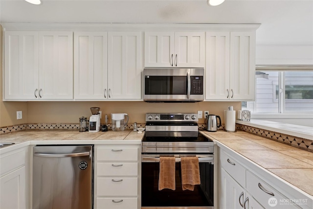 8450 25th Ave SW Unit B, Seattle, WA 98106 - kitchen featuring stainless steel appliances, white cabinetry, and tile counters