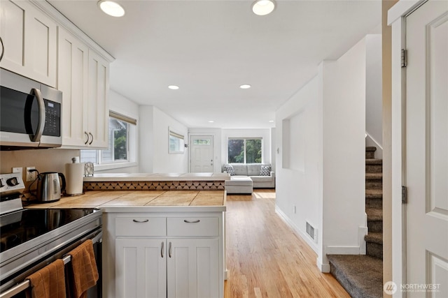 8450 25th Ave SW Unit B, Seattle, WA 98106 - kitchen featuring stainless steel appliances, light wood finished floors, healthy amount of natural light, white cabinets, and recessed lighting