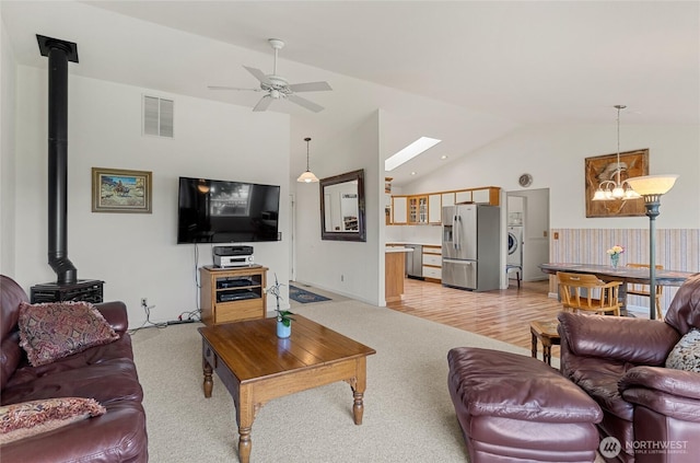 19627 Rd A NE, Soap Lake, WA 98851 - living area featuring a wood stove, vaulted ceiling, light colored carpet, a chandelier, and ceiling fan