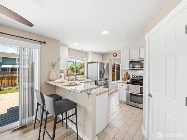535 Blanchat Ct, Enumclaw, WA 98022 - kitchen featuring stainless steel appliances, a kitchen breakfast bar, a peninsula, white cabinets, and light stone countertops