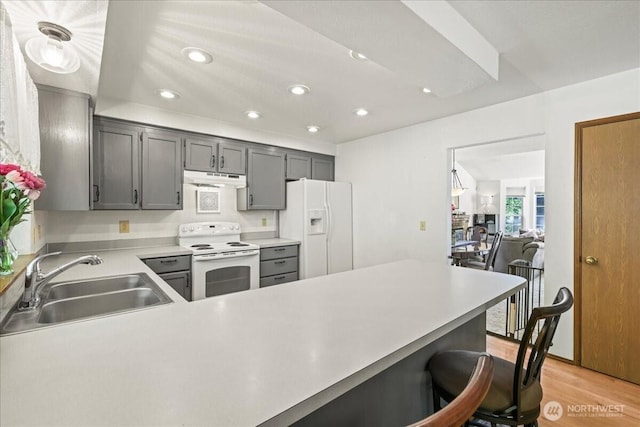 13319 15th Avenue Ct E, Tacoma, WA 98445 - kitchen with white appliances, under cabinet range hood, recessed lighting, a kitchen bar, and light countertops