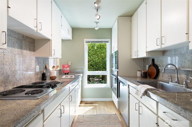 101 NW 58th St Unit 10, Seattle, WA 98107 - kitchen with stainless steel appliances, white cabinets, light wood-type flooring, and backsplash