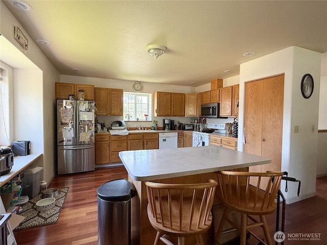 16 River Overlook St, Omak, WA 98841 - kitchen with appliances with stainless steel finishes, dark wood-style floors, a breakfast bar area, light countertops, and brown cabinetry