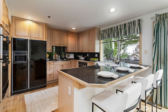 10135 NE 64th St Unit A, Kirkland, WA 98033 - kitchen featuring black fridge with ice dispenser, light brown cabinetry, light wood-style flooring, recessed lighting, and a breakfast bar area