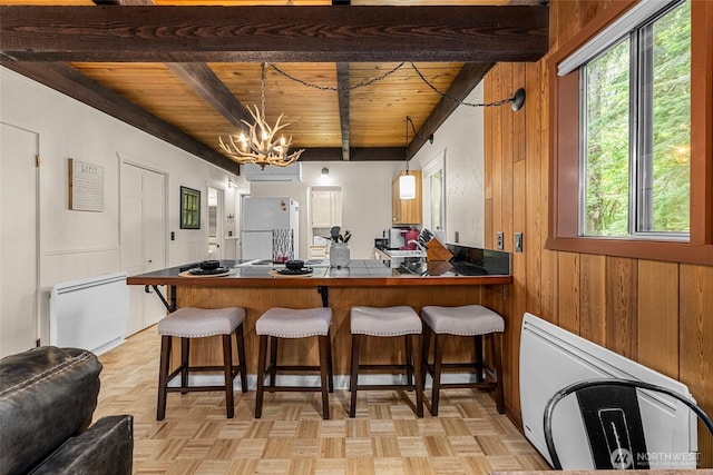 18690 Rieche Rd, Lake Wenatchee, WA 98826 - kitchen featuring freestanding refrigerator, a wood ceiling with exposed beams, plenty of natural light, wooden walls, and a breakfast bar