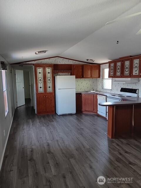900 N Grape Dr Unit 36, Moses Lake, WA 98337 - kitchen with white appliances, lofted ceiling, a peninsula, dark wood-type flooring, and under cabinet range hood