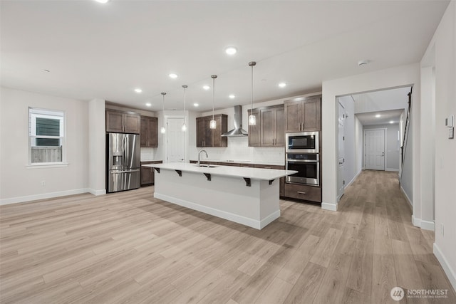 20424 E 97th Ave E Unit 6, Graham, WA 98338 - kitchen with appliances with stainless steel finishes, wall chimney range hood, light countertops, light wood finished floors, and a kitchen bar